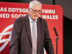 A man in a suit at a lectern delivering a speech.