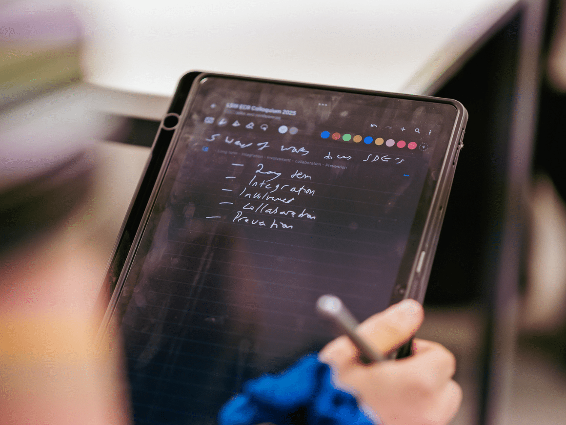Someone holding a tablet with some notes written on it.