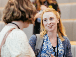 A woman smiling while in conversation with another woman.