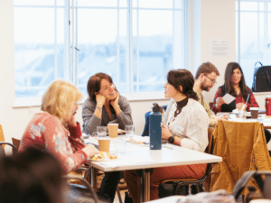 A room with two tables, people sitting around them deep in conversation