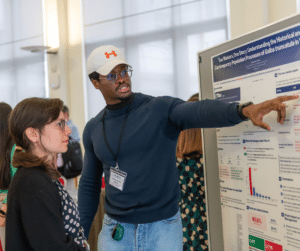 A man pointing at a poster while talking to a woman.
